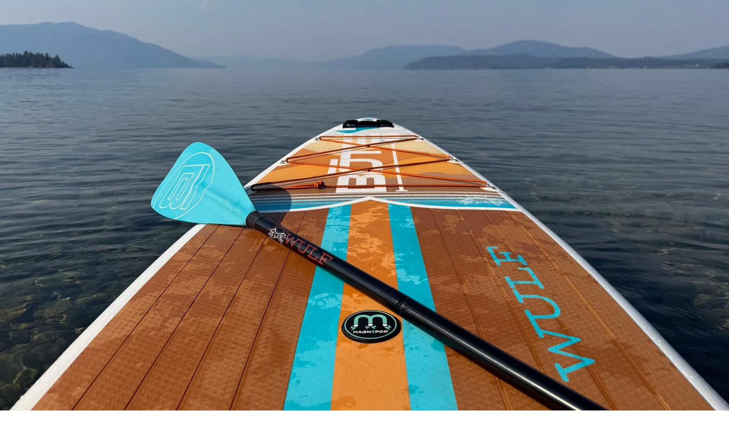 Looking down the nose of a paddleboard across a calm mountain lake
