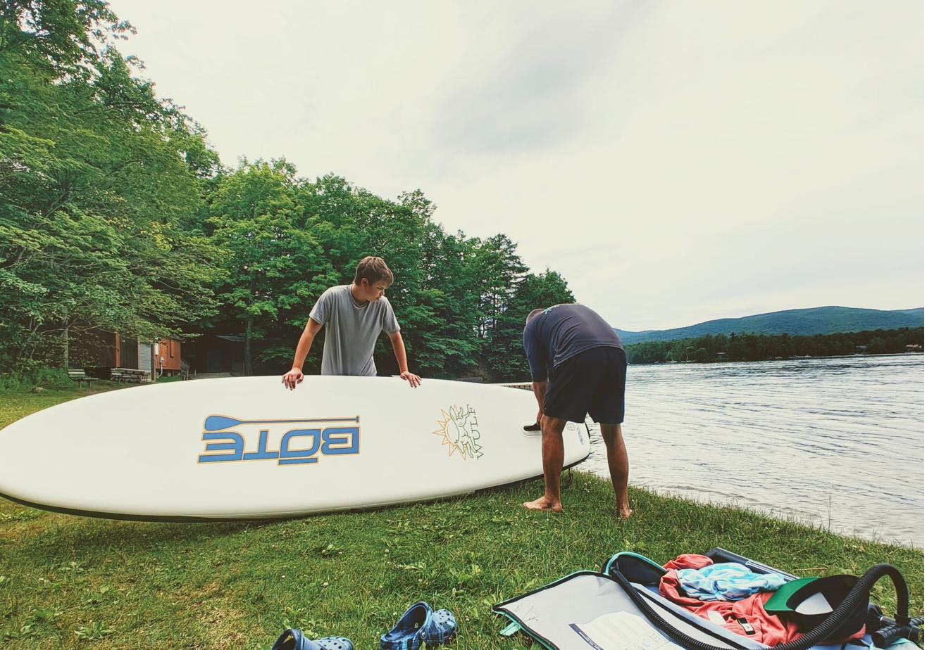 Setting up a paddleboard at the edge of a Berkshire lake with mountains behind